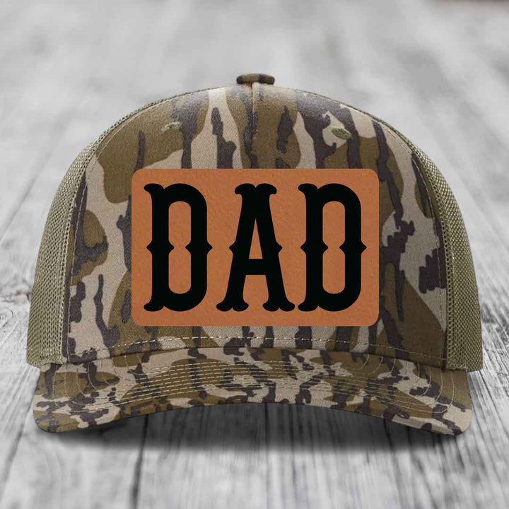 Blue and white trucker hat with brown leather patch that says DAD in black letters.
