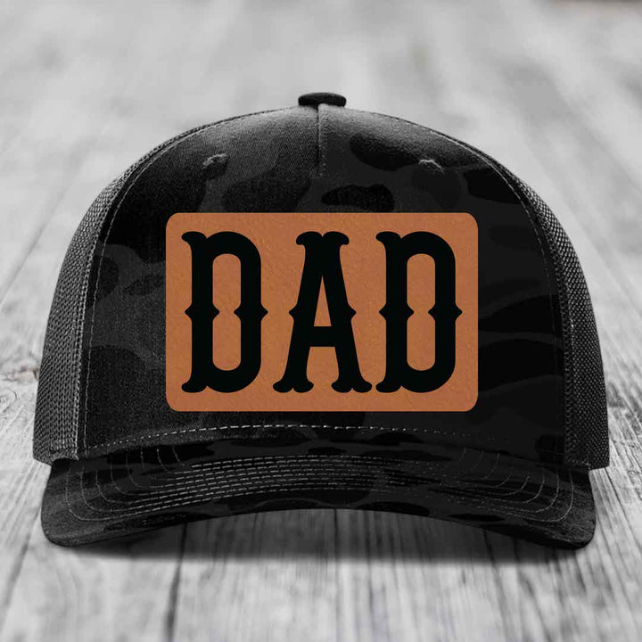 Camouflage trucker hat with brown leather patch reading &