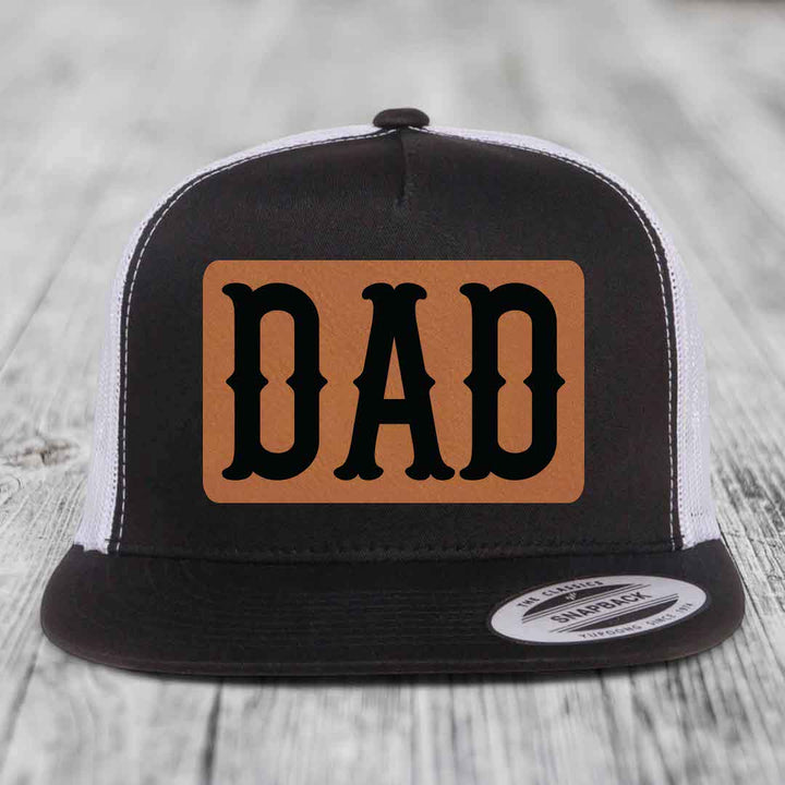 Grey trucker hat with brown leather patch that says DAD in black letters.