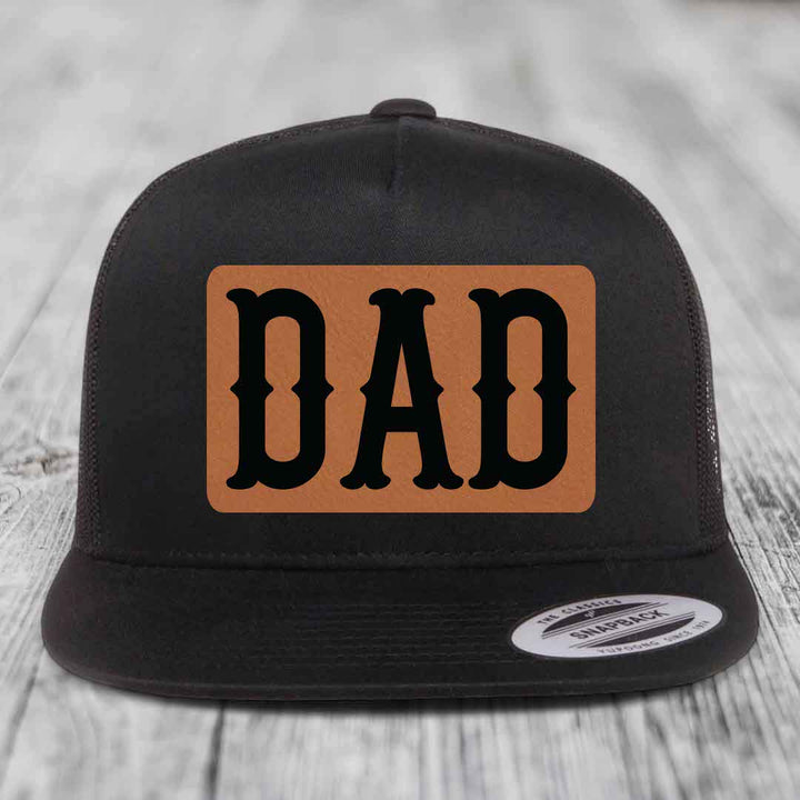 Black and white trucker hat with brown leather patch that says DAD in black letters.