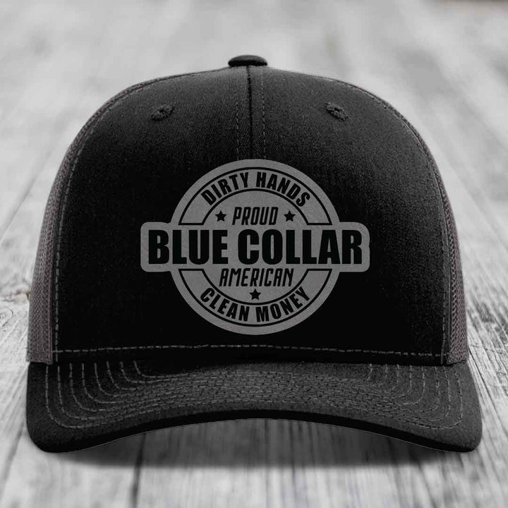 Black trucker hat with white mesh back and stitching, featuring a circular &