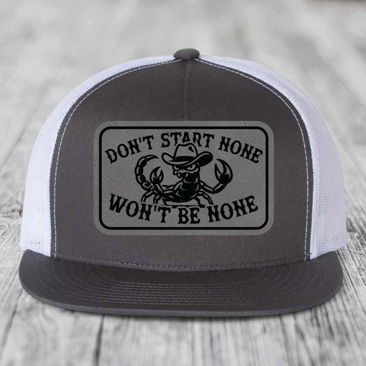 Grey and white trucker hat with black leatherette patch featuring scorpion wearing cowboy hat and text &