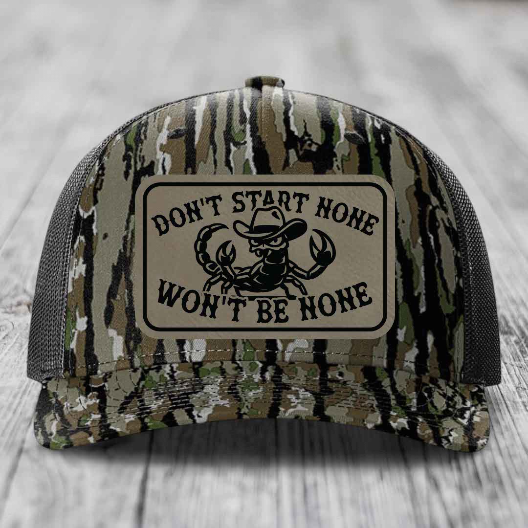 Camouflage trucker hat with a tan leatherette patch that says &