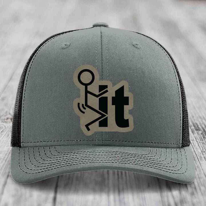 Grey trucker hat with black mesh back and a beige leather patch featuring a stick figure and the word &