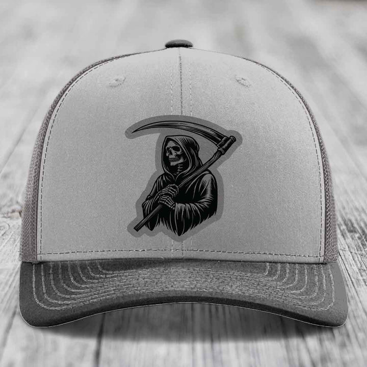 Grey trucker hat with black Grim Reaper patch holding scythe.