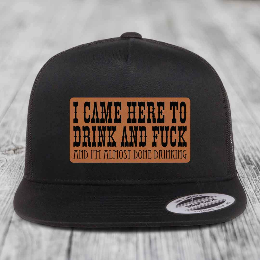 Black trucker hat with brown leather patch reading &