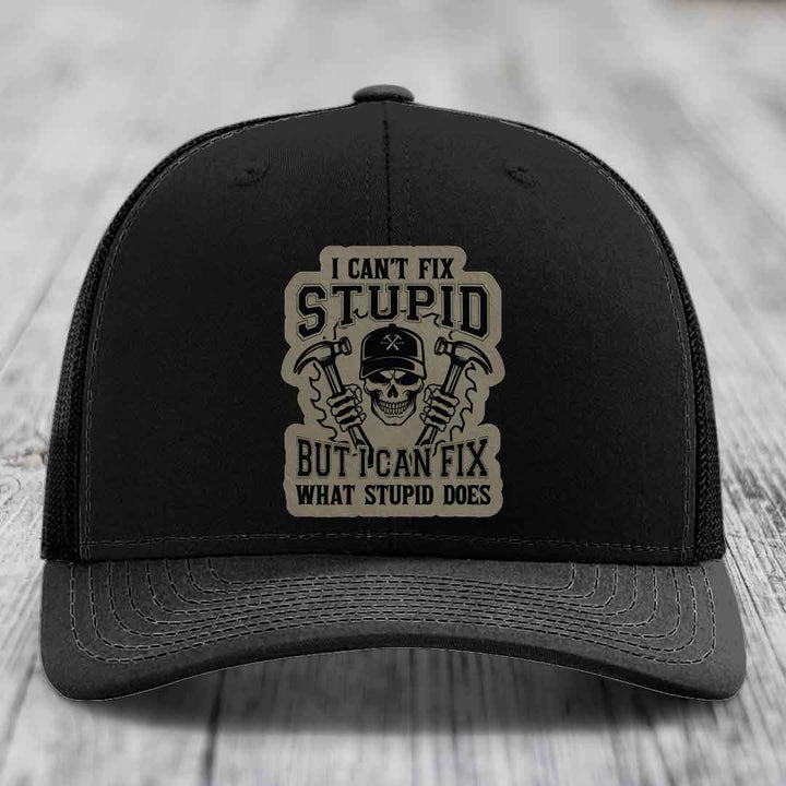 Black trucker hat with beige patch featuring skull holding hammers and text: &