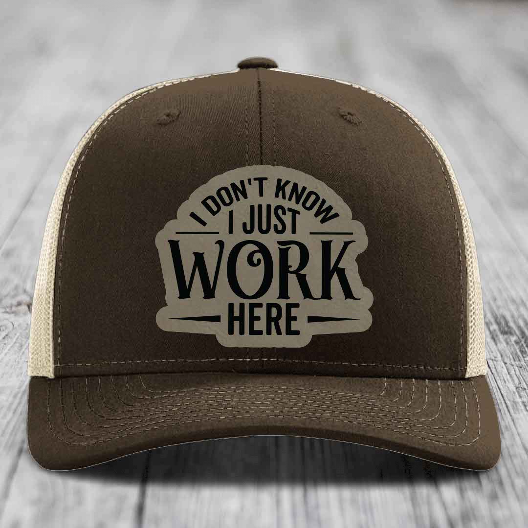 Brown trucker hat with cream mesh back and black embroidered patch reading &