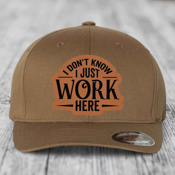 Tan baseball cap with brown leatherette patch reading &