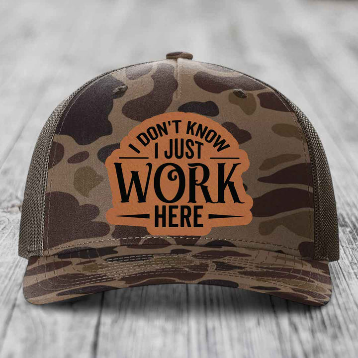 Camouflage trucker hat with brown leatherette patch reading &