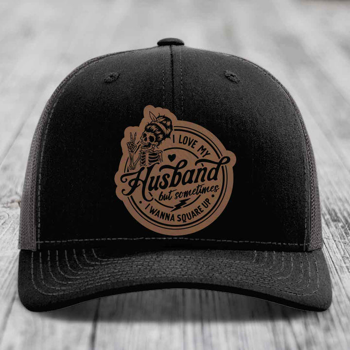 Black trucker hat with brown leather patch featuring skeleton graphic and text &
