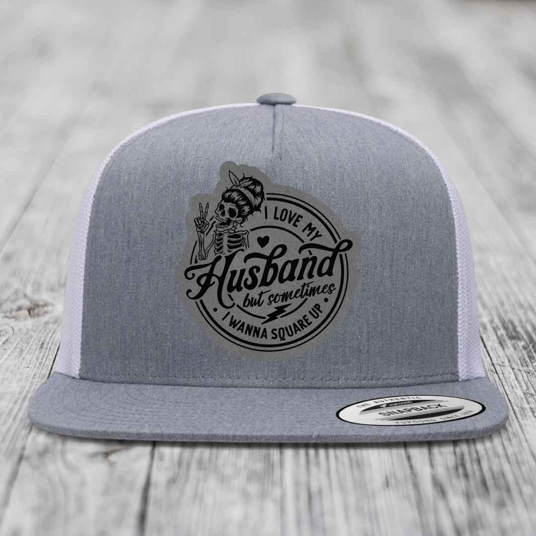 Grey trucker hat with black skull patch reading &