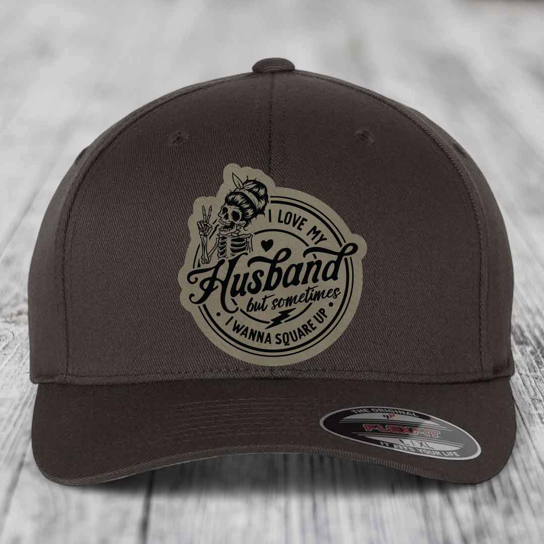 Dark brown Flexfit hat with a circular patch featuring a skeleton holding peace signs and the text &