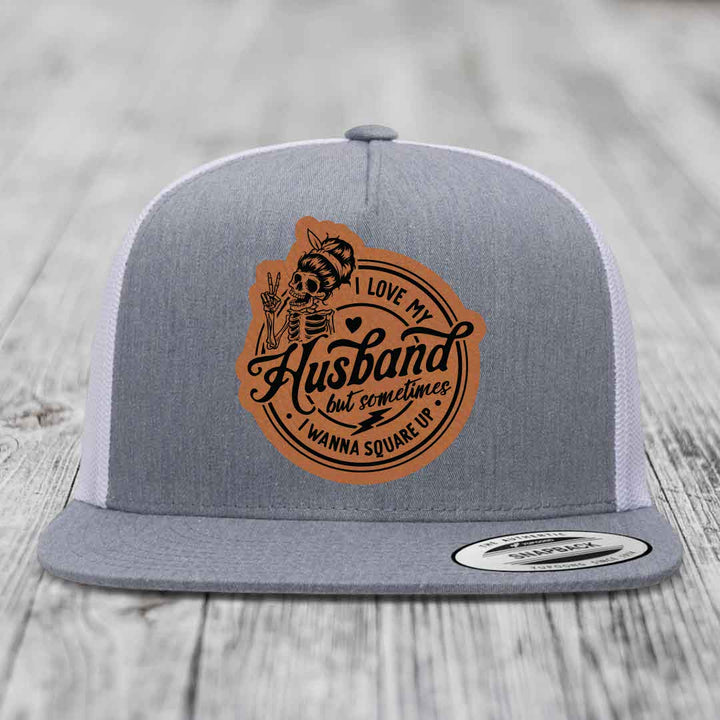 Grey trucker hat with brown leather patch featuring skeleton and text &