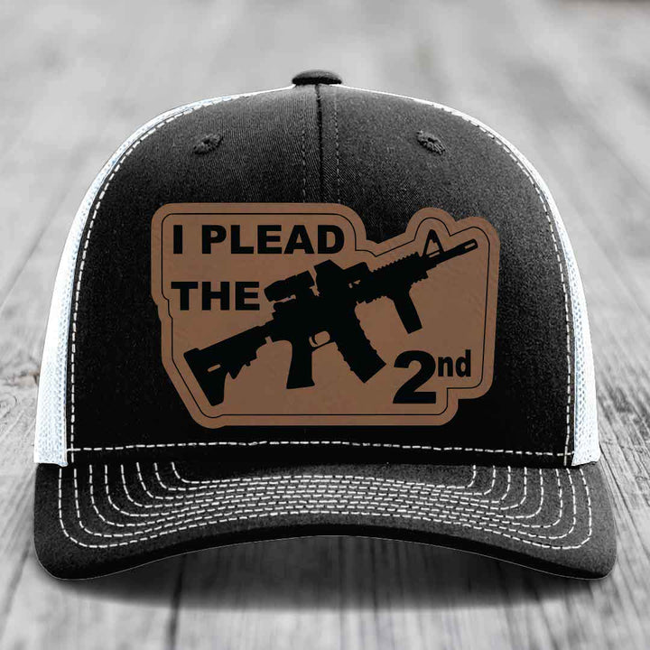 Black and white trucker hat with brown leather patch reading &