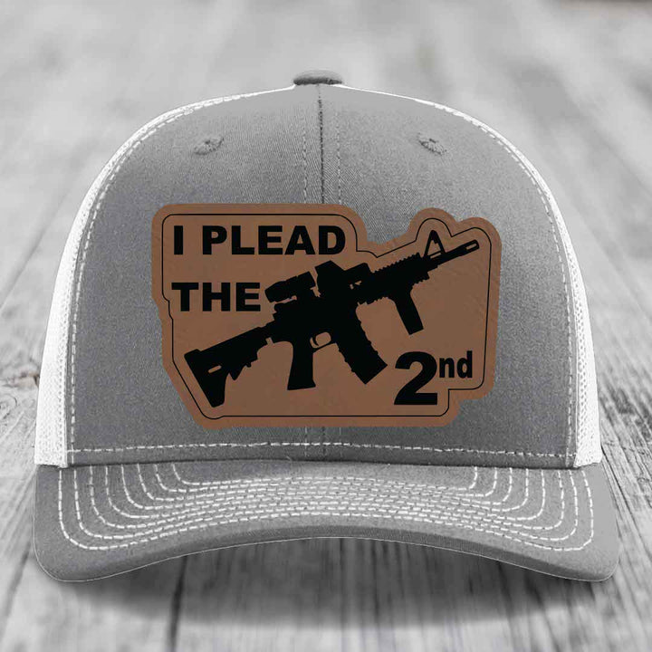 Grey trucker hat with brown leather patch reading &