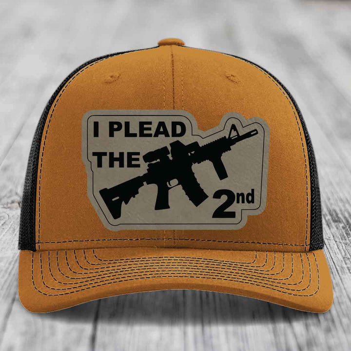 Tan trucker hat with black mesh back and a gray patch that says &
