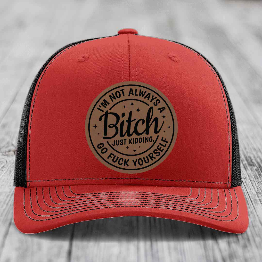 Red trucker hat with black mesh back and a circular leatherette patch reading &