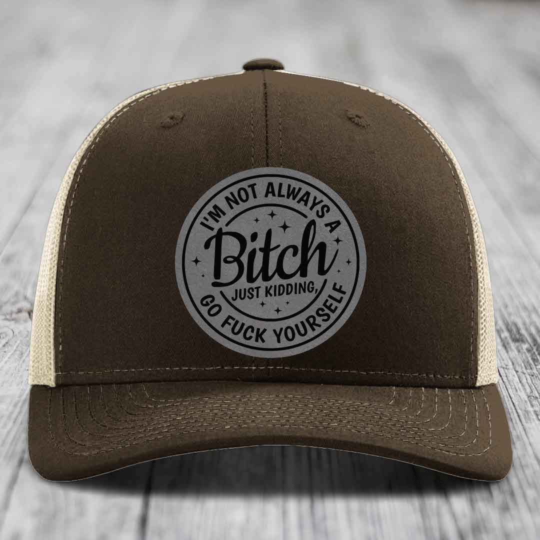 Brown trucker hat with cream mesh back and gray circular patch reading &