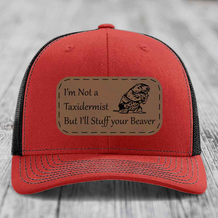 Red trucker hat with black mesh back and a brown leather patch that reads &