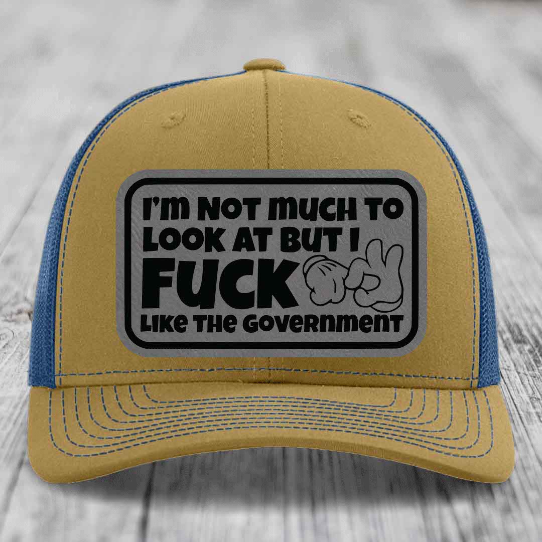Tan and blue trucker hat with a gray rectangular patch that reads &