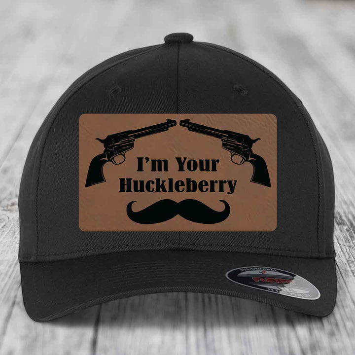 Black baseball cap with brown leather patch featuring two revolvers, text &