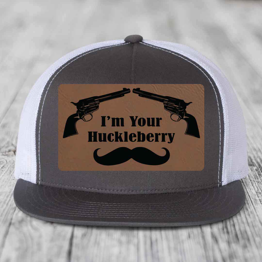 Grey and white trucker hat with brown leather patch featuring two revolvers, text &