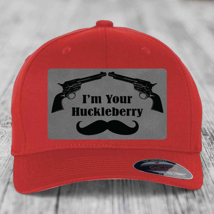 Red baseball cap with grey patch featuring two revolvers, text &