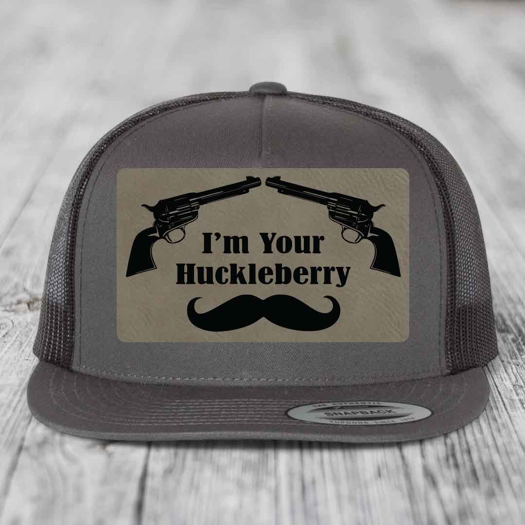 Grey trucker hat with black leatherette patch featuring two revolvers, text &