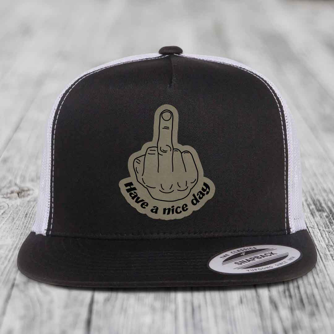 Black and white trucker hat with a beige leatherette patch of a middle finger and text &