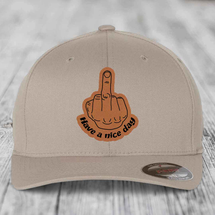 Beige baseball cap with brown leather patch showing middle finger and text &