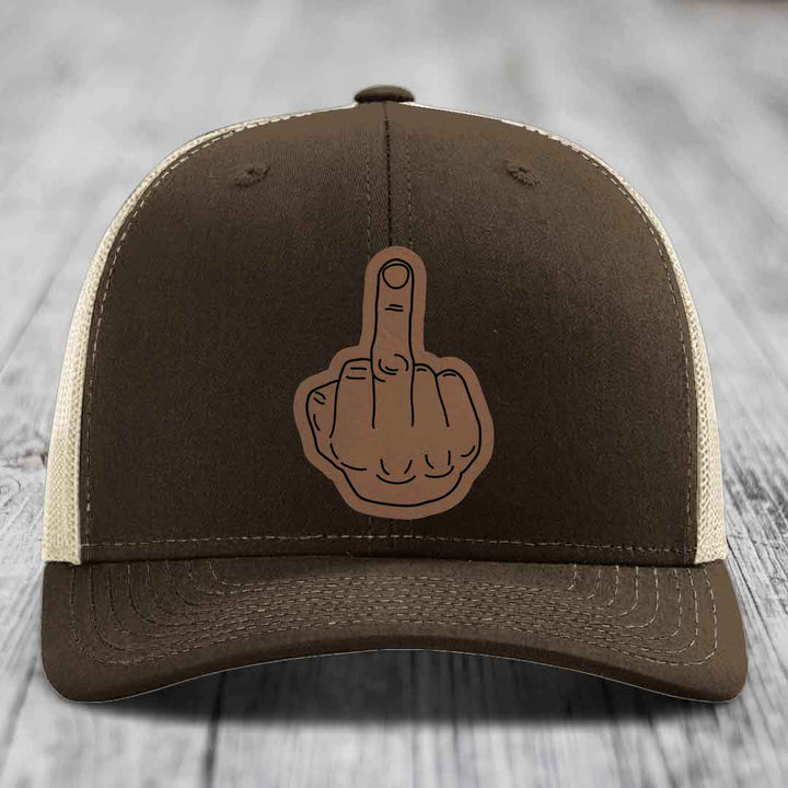 Brown trucker hat with beige mesh back and a brown leatherette middle finger patch on front.