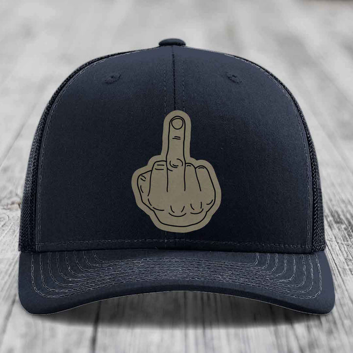 Black trucker hat with a beige middle finger patch on the front.