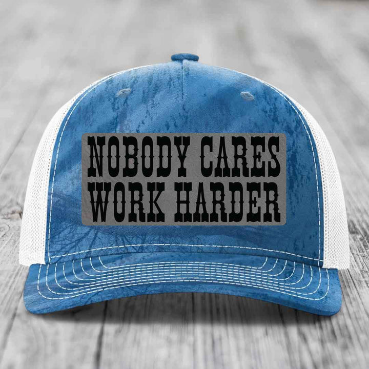 Blue and white trucker hat with a gray leather patch that reads &