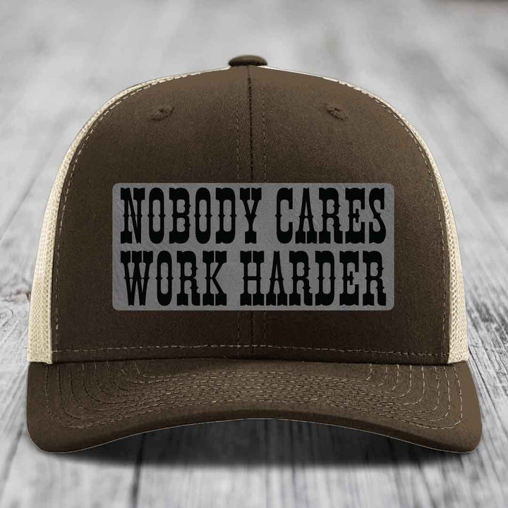 Brown trucker hat with beige mesh back and black embroidered patch reading &