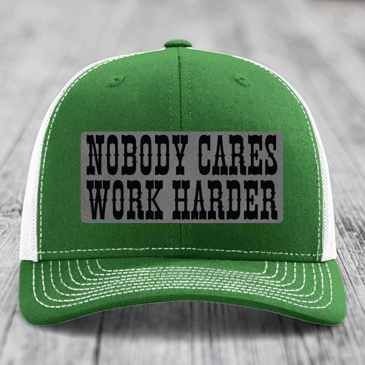 Green trucker hat with white mesh back and brim, featuring a grey patch with black text reading &