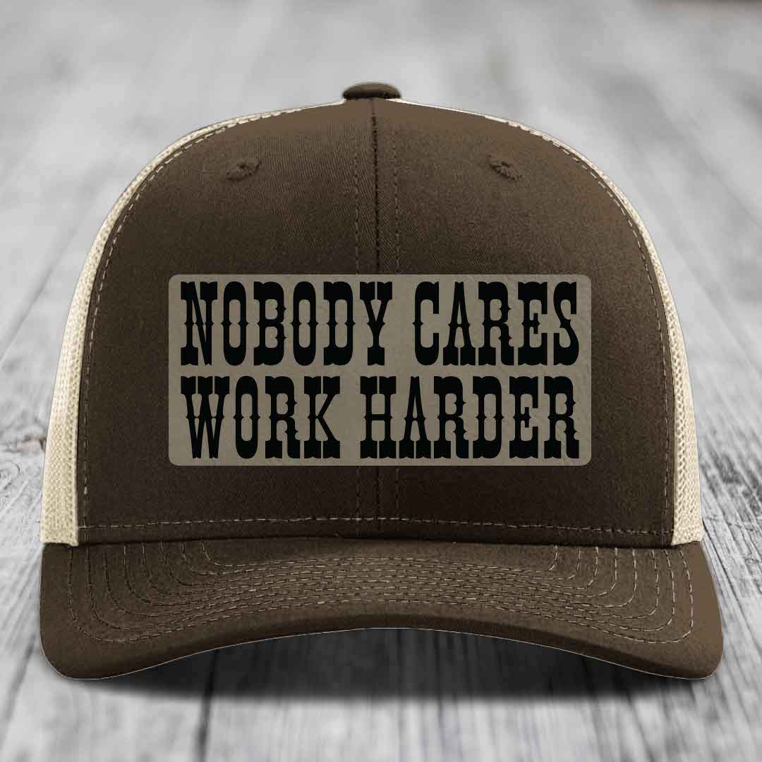 Brown trucker hat with beige mesh back and black embroidered patch reading &