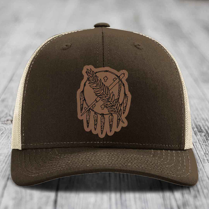 Brown trucker hat with beige mesh back and a brown leather patch featuring a dreamcatcher design.