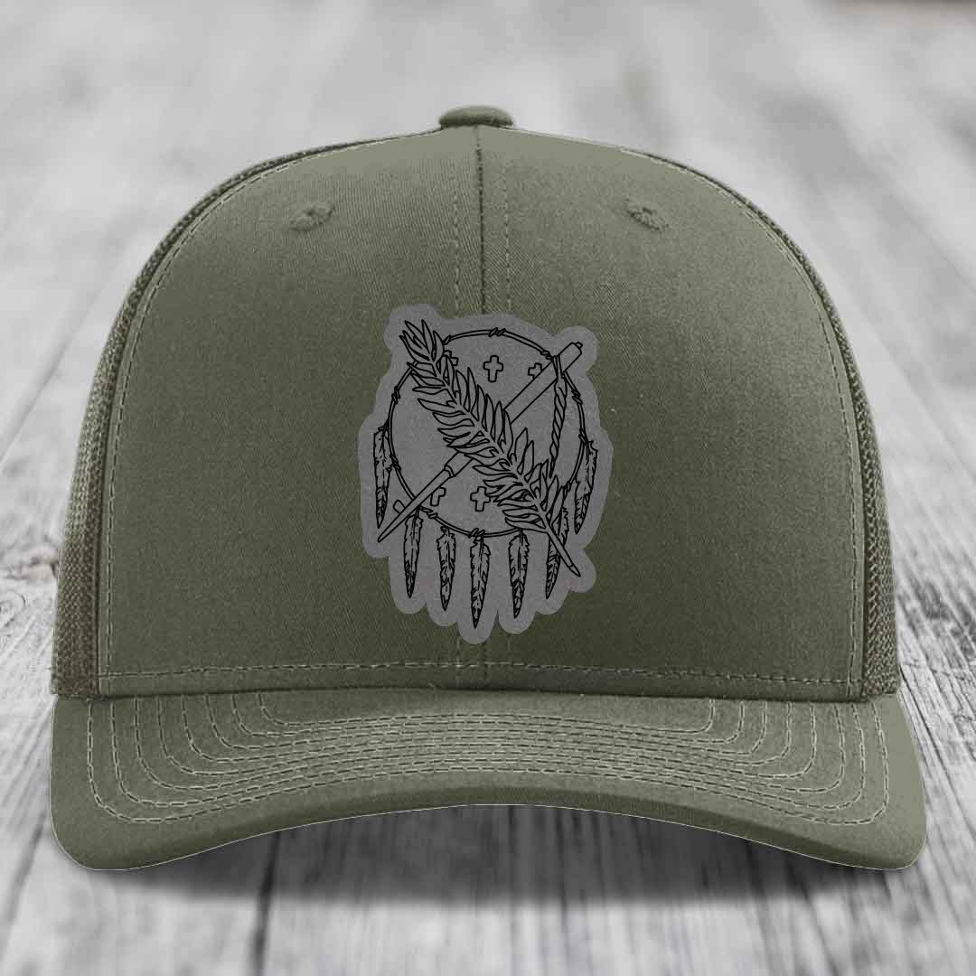 Olive green trucker hat with a grey dreamcatcher patch featuring feathers and crosses.