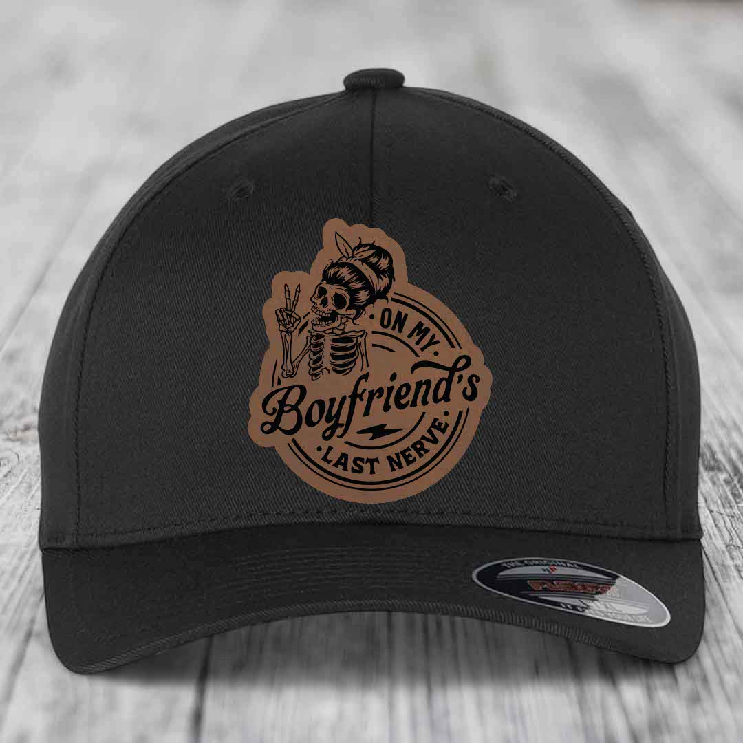 Black baseball cap with brown leather patch featuring skeleton holding peace sign and text &