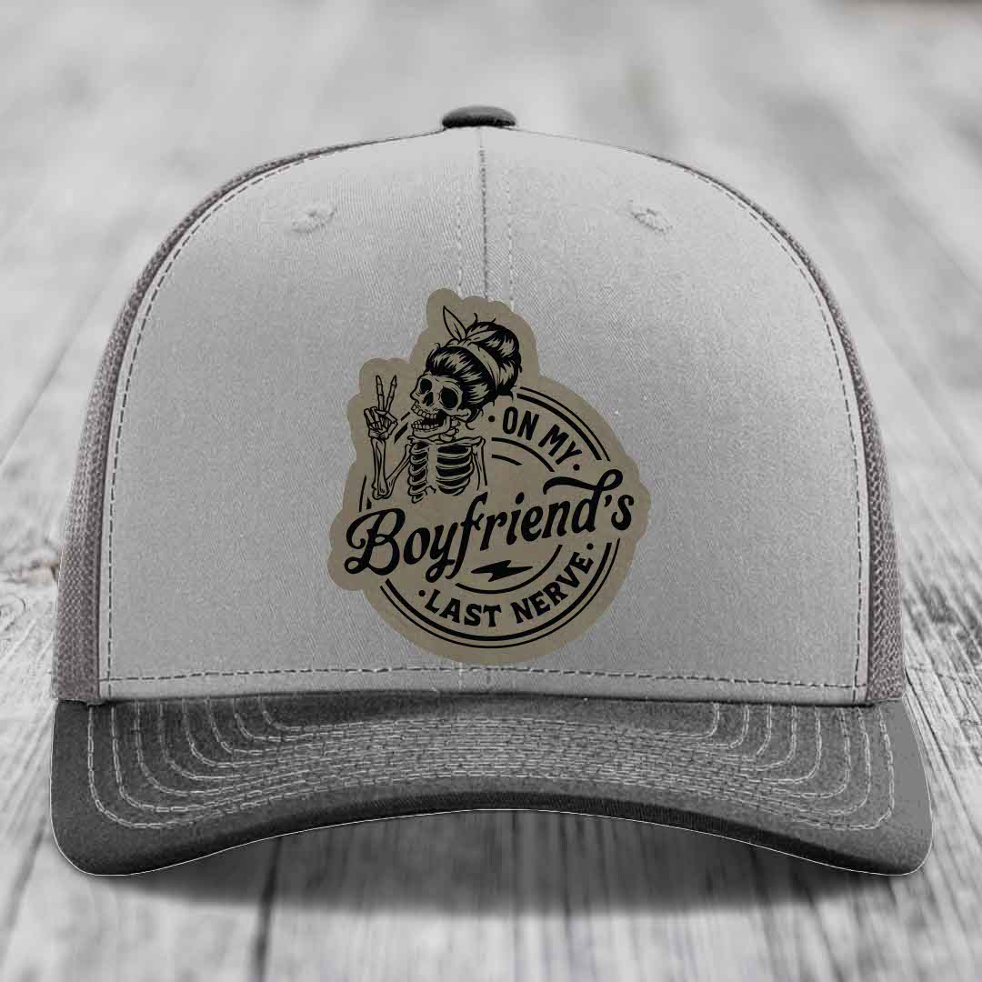 Grey trucker hat with a skull patch reading &