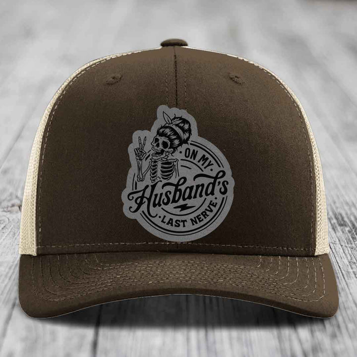 Brown trucker hat with beige mesh back and gray patch featuring skeleton holding peace sign with text &