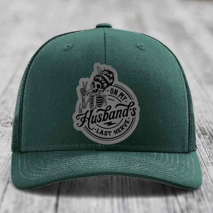Green trucker hat with a grey patch featuring a skeleton holding peace sign and text &