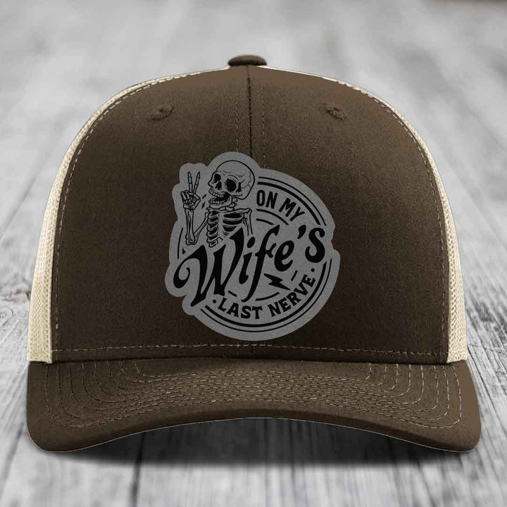 Brown trucker hat with beige mesh back and gray skull patch reading &
