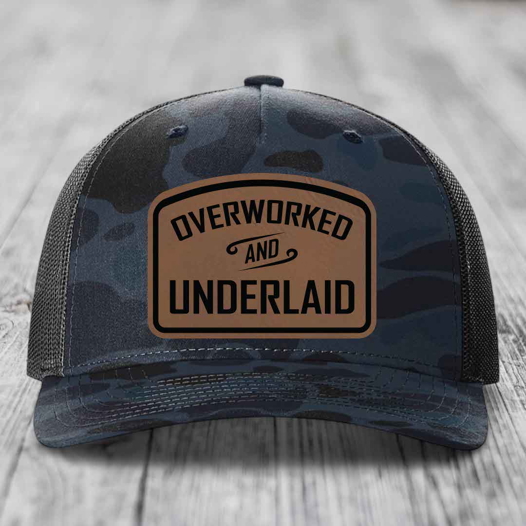 Camouflage trucker hat with brown leather patch reading &