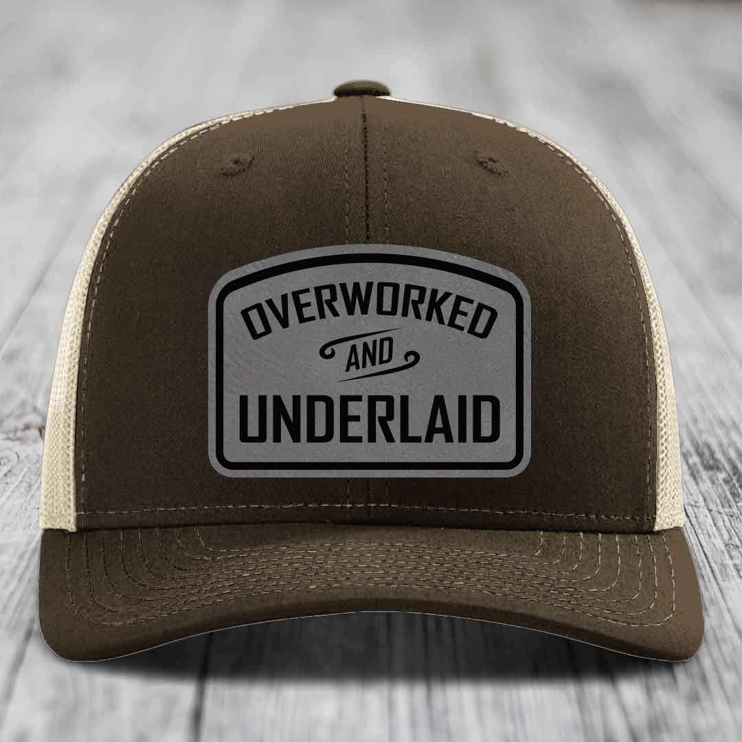 Brown trucker hat with beige mesh back and gray leatherette patch reading &