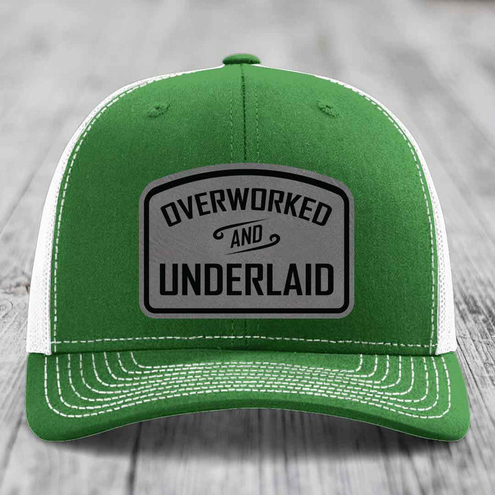 Green trucker hat with white mesh back and gray leatherette patch reading &