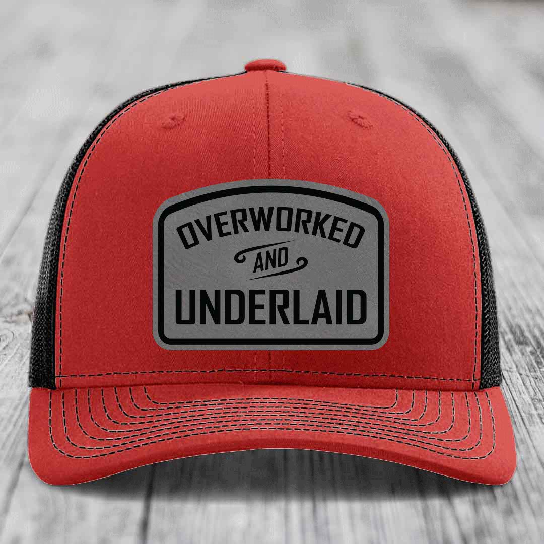 Red trucker hat with black mesh back and gray leatherette patch reading &