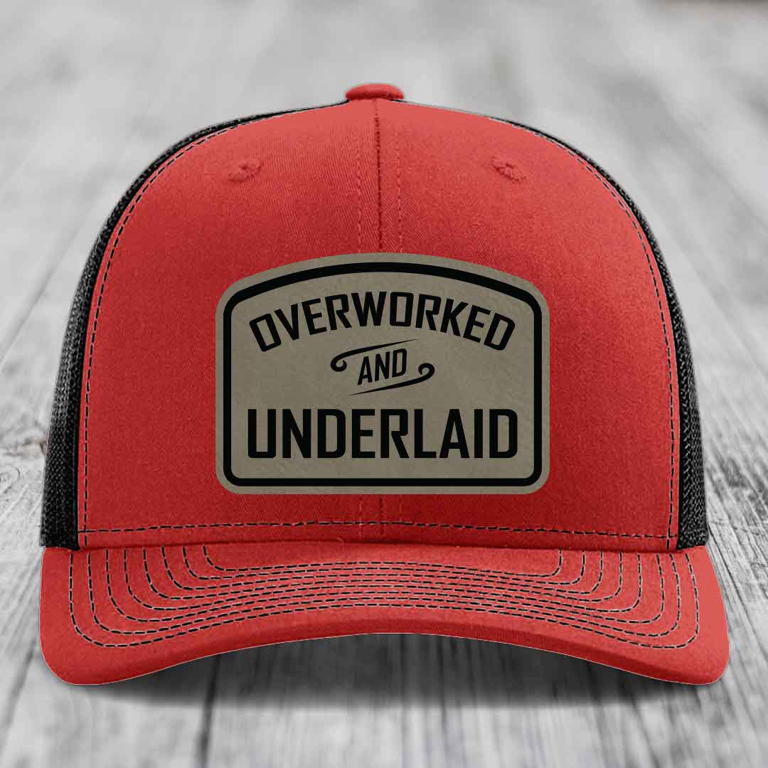 Red trucker hat with black mesh back and beige leatherette patch reading &