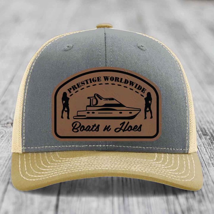 Grey and beige trucker hat with brown leather patch featuring &
